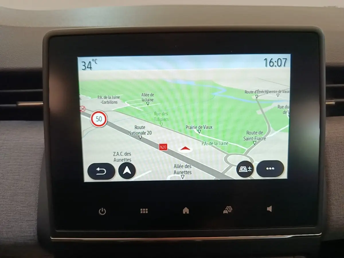 Écran tactile central affichant la navigation GPS dans un Renault Clio gris clair, vue intérieure frontale.