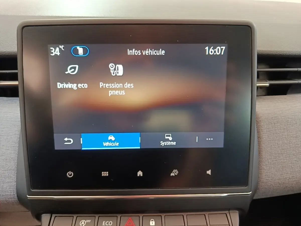 Écran tactile central affichant les infos véhicule dans l’habitacle d’une Renault Clio gris clair, vue de face.