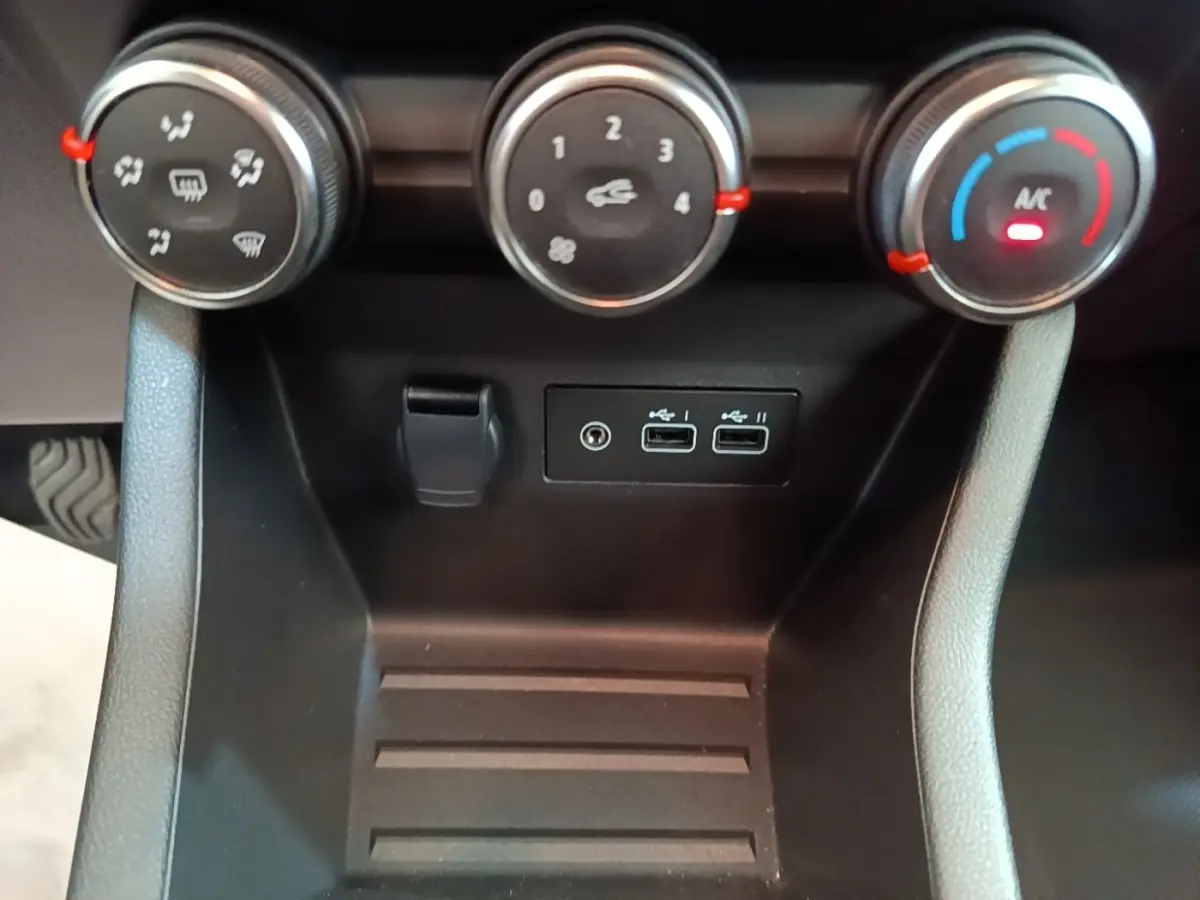 Vue rapprochée du tableau de bord de la Renault Clio gris clair 2025, montrant les commandes de climatisation et ports USB.