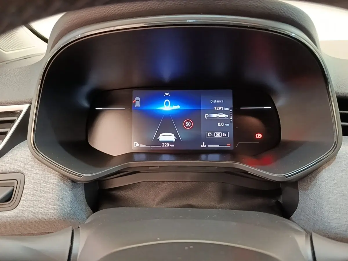 Vue rapprochée du combiné d'instruments numérique de la Renault Clio gris clair, affichant la vitesse et l'assistance à la conduite.