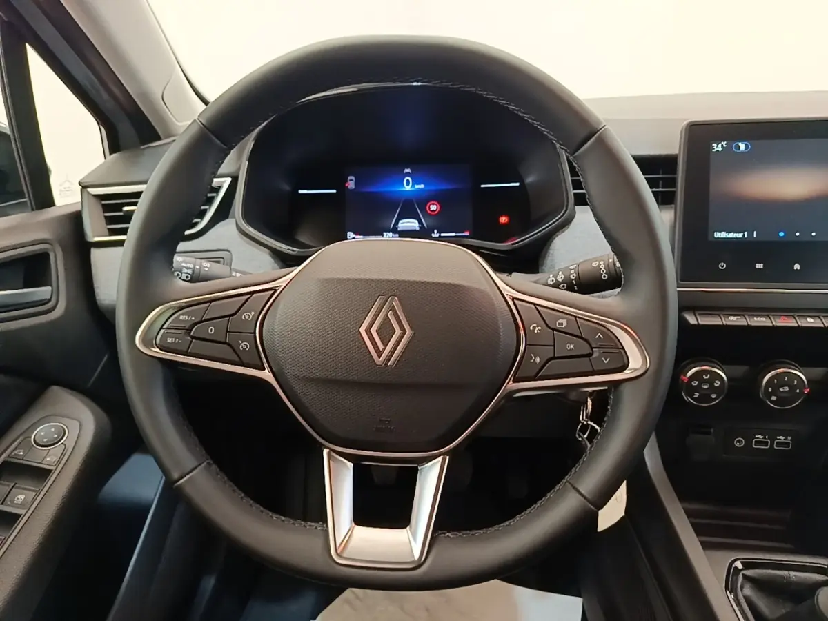 Vue intérieure centrée sur le volant cuir multifonctions et le tableau de bord digital de la Renault Clio gris clair 2025.