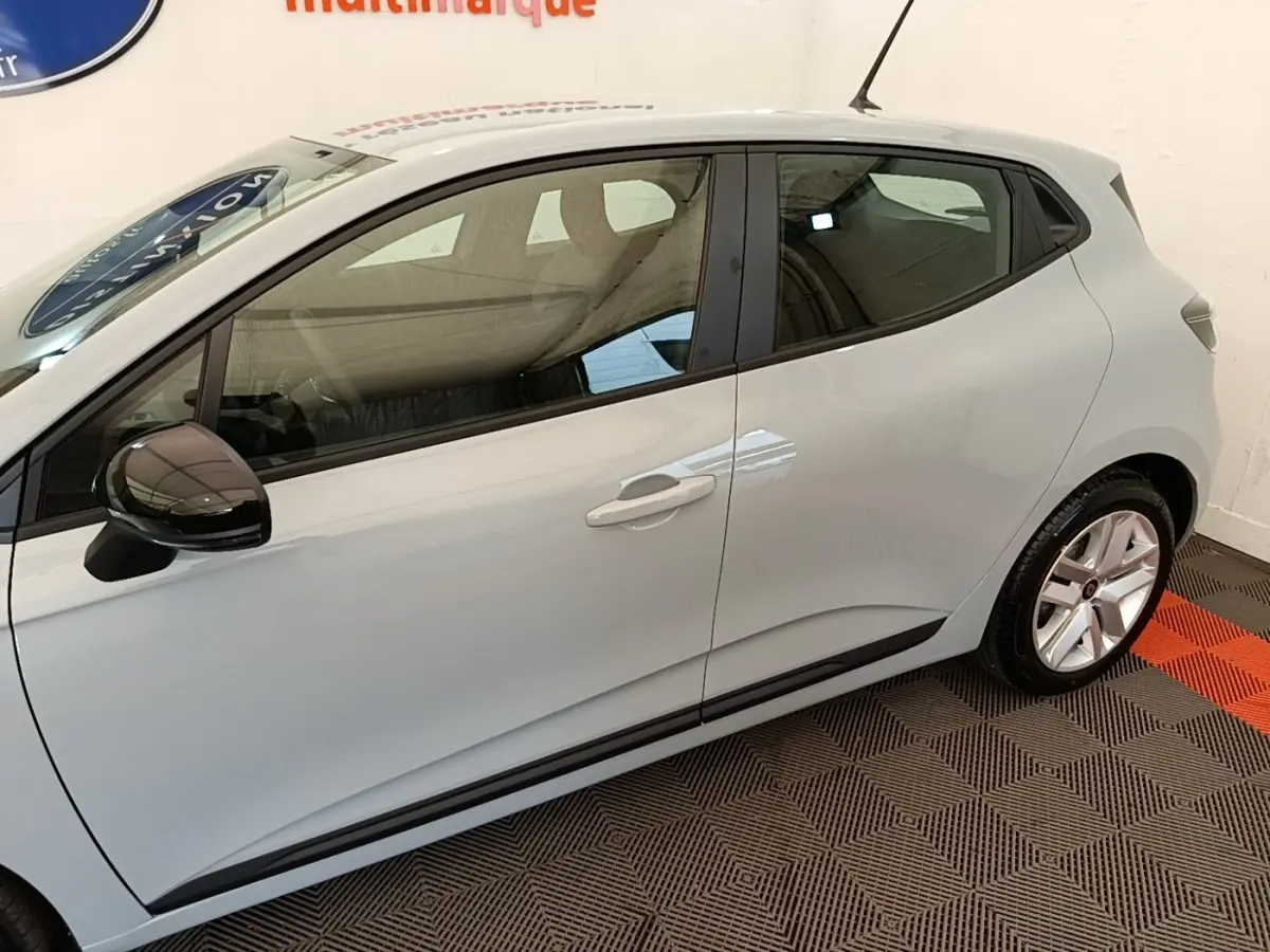 Vue de profil côté gauche d'une Renault Clio gris clair avec rétroviseur noir et jantes alliage.