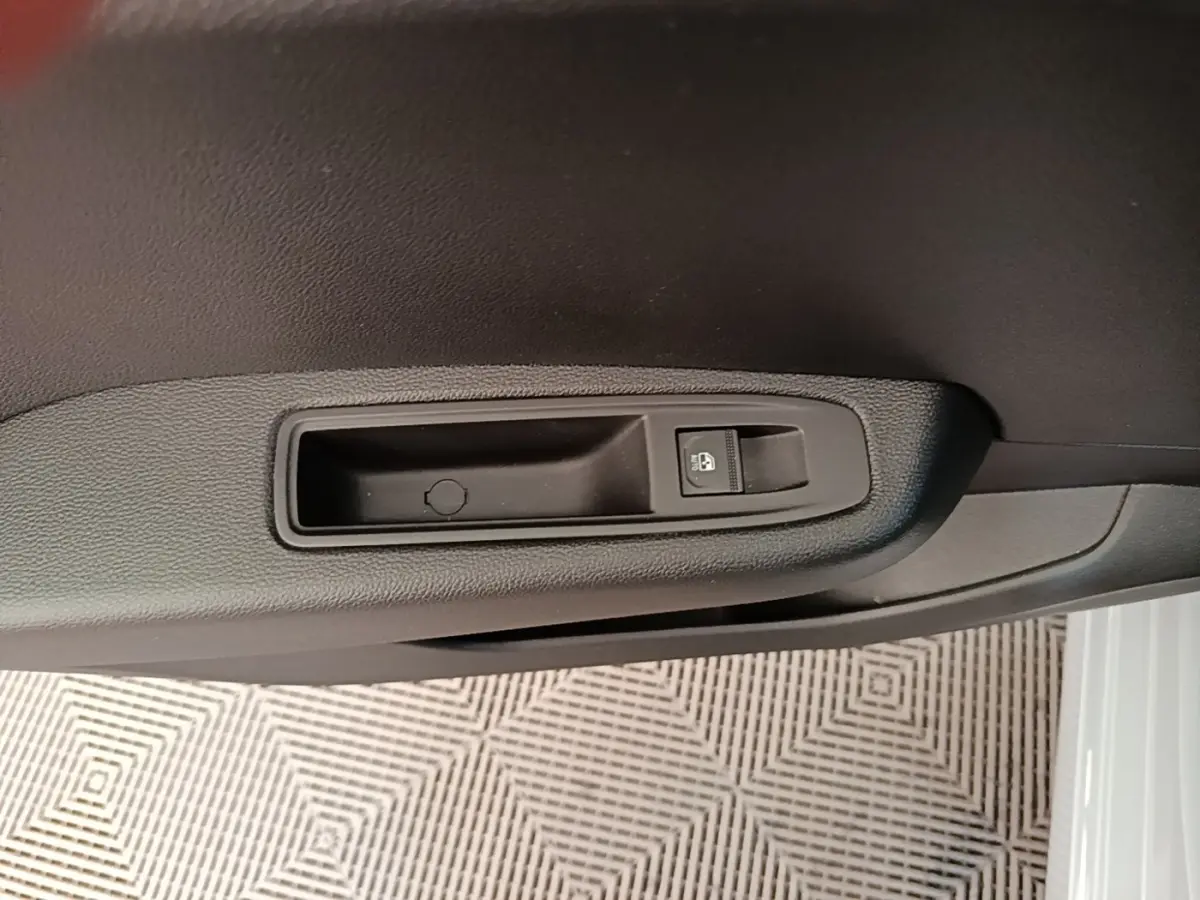 Gros plan sur la commande de verrouillage des portes côté conducteur d’une Renault Clio gris clair, intérieur noir.