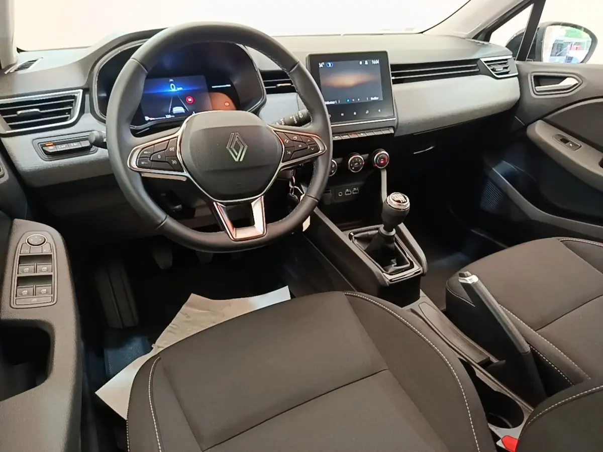 Vue intérieure avant de la Renault Clio gris clair 2025, volant cuir multifonctions et écran tactile central.