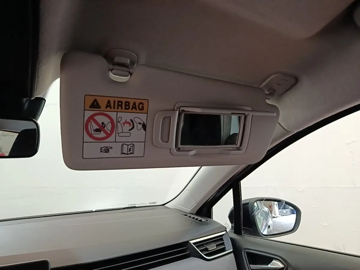 Intérieur de la Renault Clio gris clair, vue côté passager avec pare-soleil ouvert et miroir intégré.