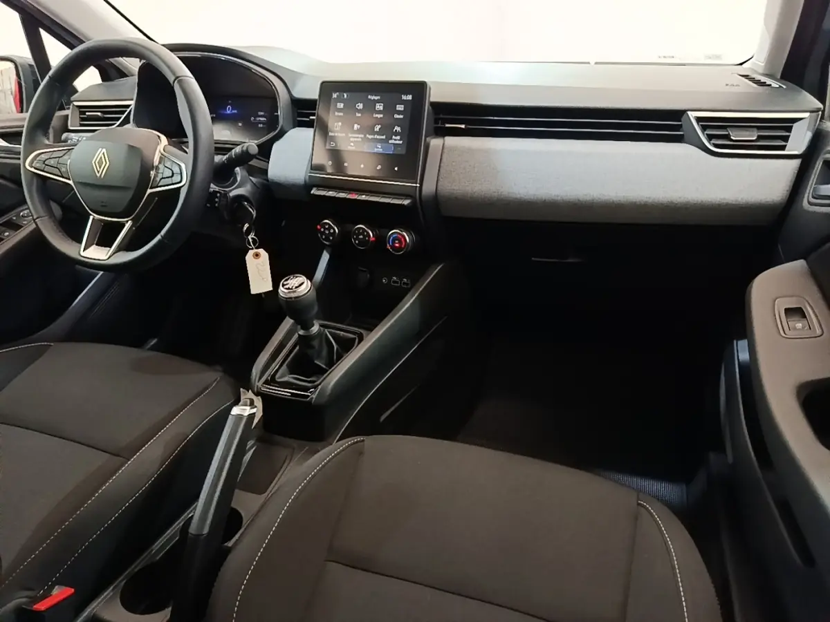 Vue intérieure avant droite de la Renault Clio gris clair, volant cuir multifonctions, écran tactile central et boîte manuelle.
