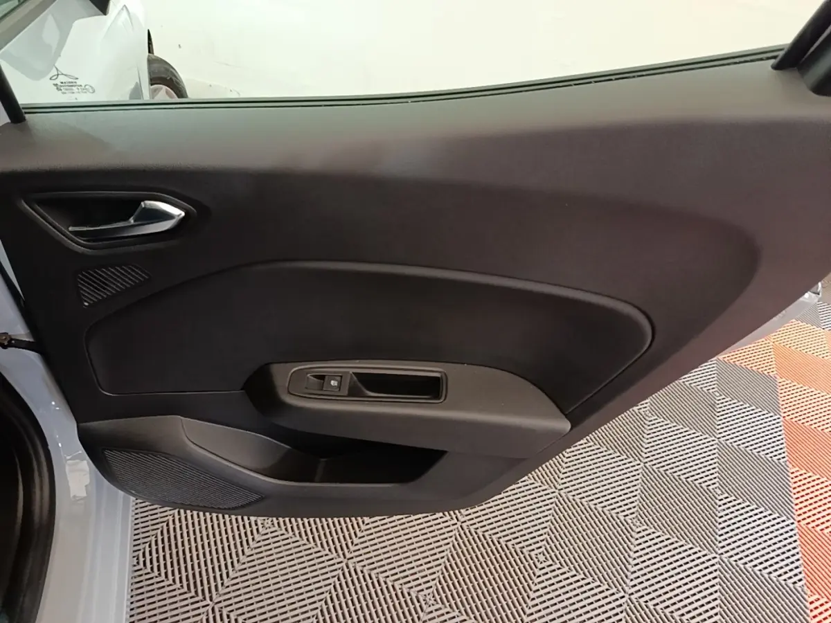 Vue intérieure du panneau de porte côté gauche de la Renault Clio gris clair, avec poignée et commande de fenêtre électrique.