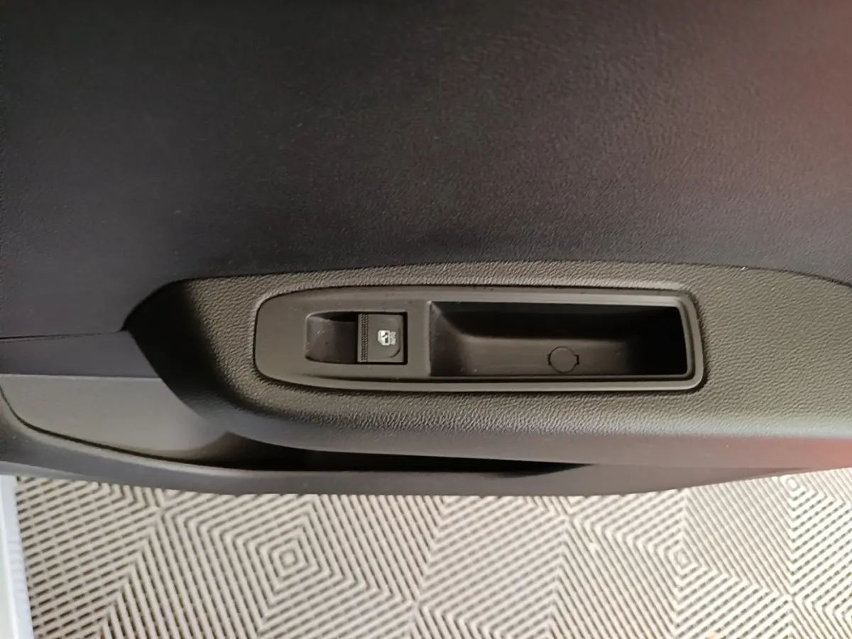 Gros plan sur la commande de verrouillage de porte côté intérieur d’une Renault Clio gris clair, version 2025.