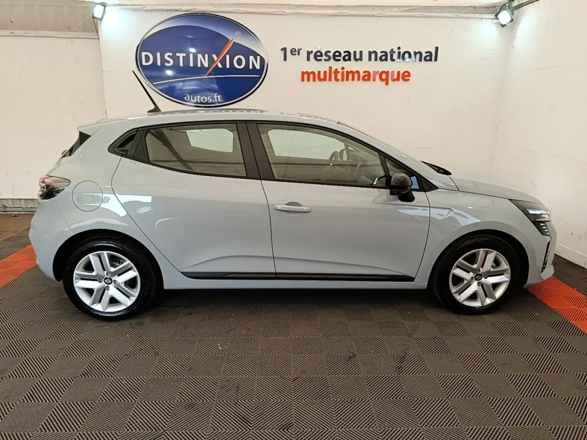 Profil côté droit de la Renault Clio Evolution dCi 100 gris clair 2025, avec jantes alliage et toit avec spoiler.