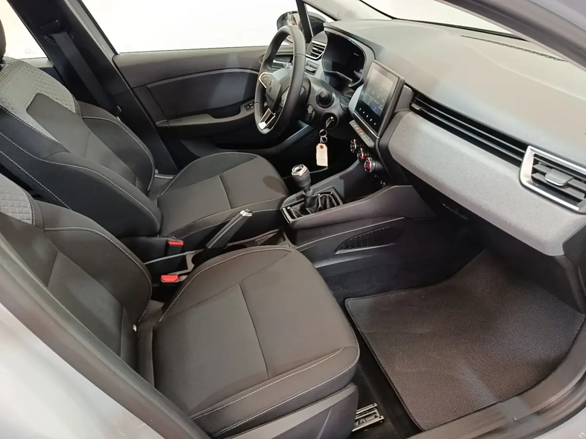 Vue intérieure côté conducteur de la Renault Clio gris clair 2025, avec sièges noirs et tableau de bord moderne.