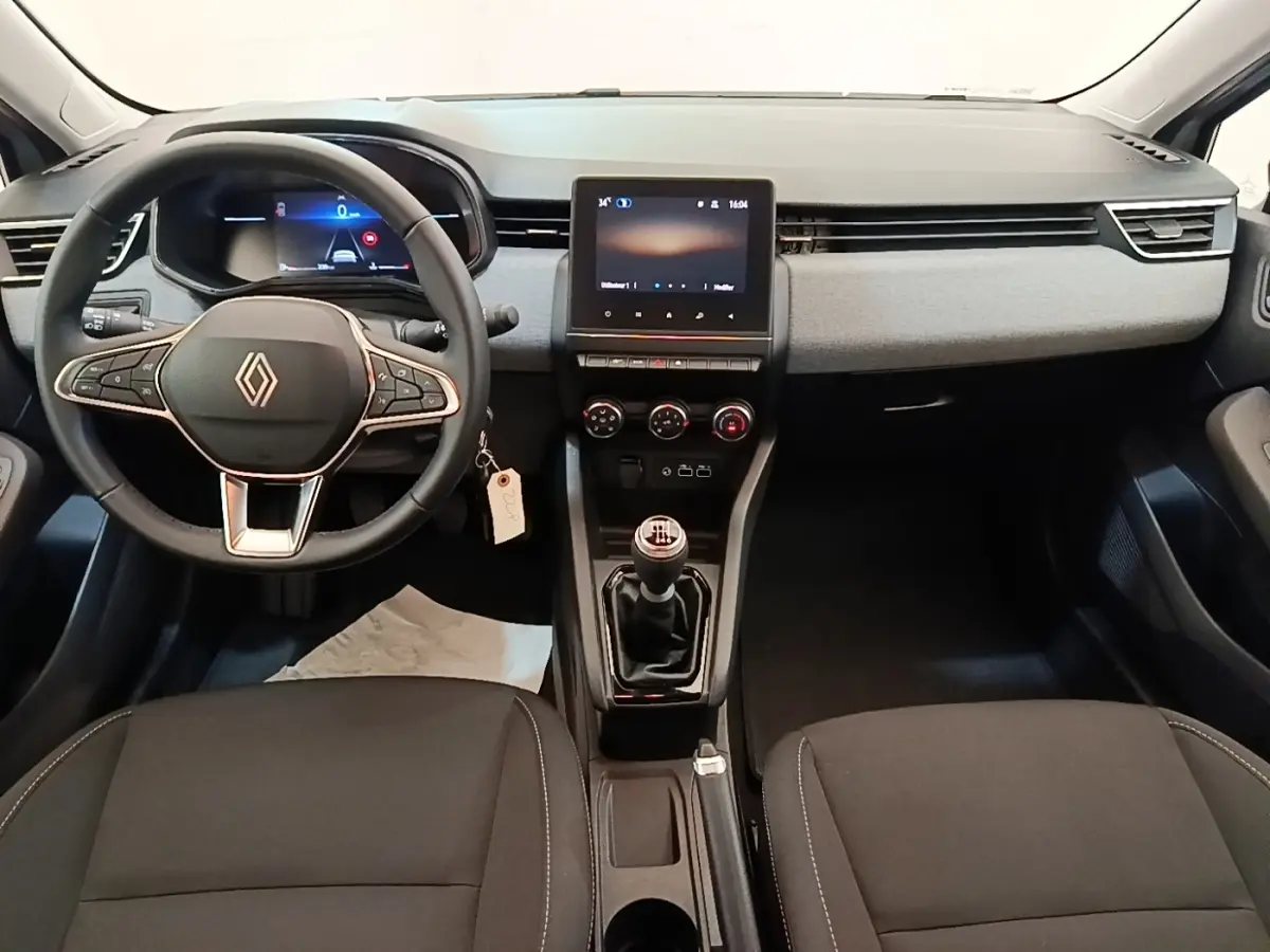 Vue intérieure avant de la Renault Clio 2025 avec volant multifonctions cuir synthétique et écran tactile central.