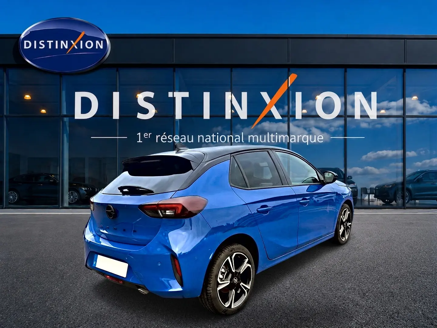 Vue 3/4 arrière droite d'une Opel Corsa bleu 2025 avec toit noir et jantes alu distinctives, devant une vitrine Distinxion.