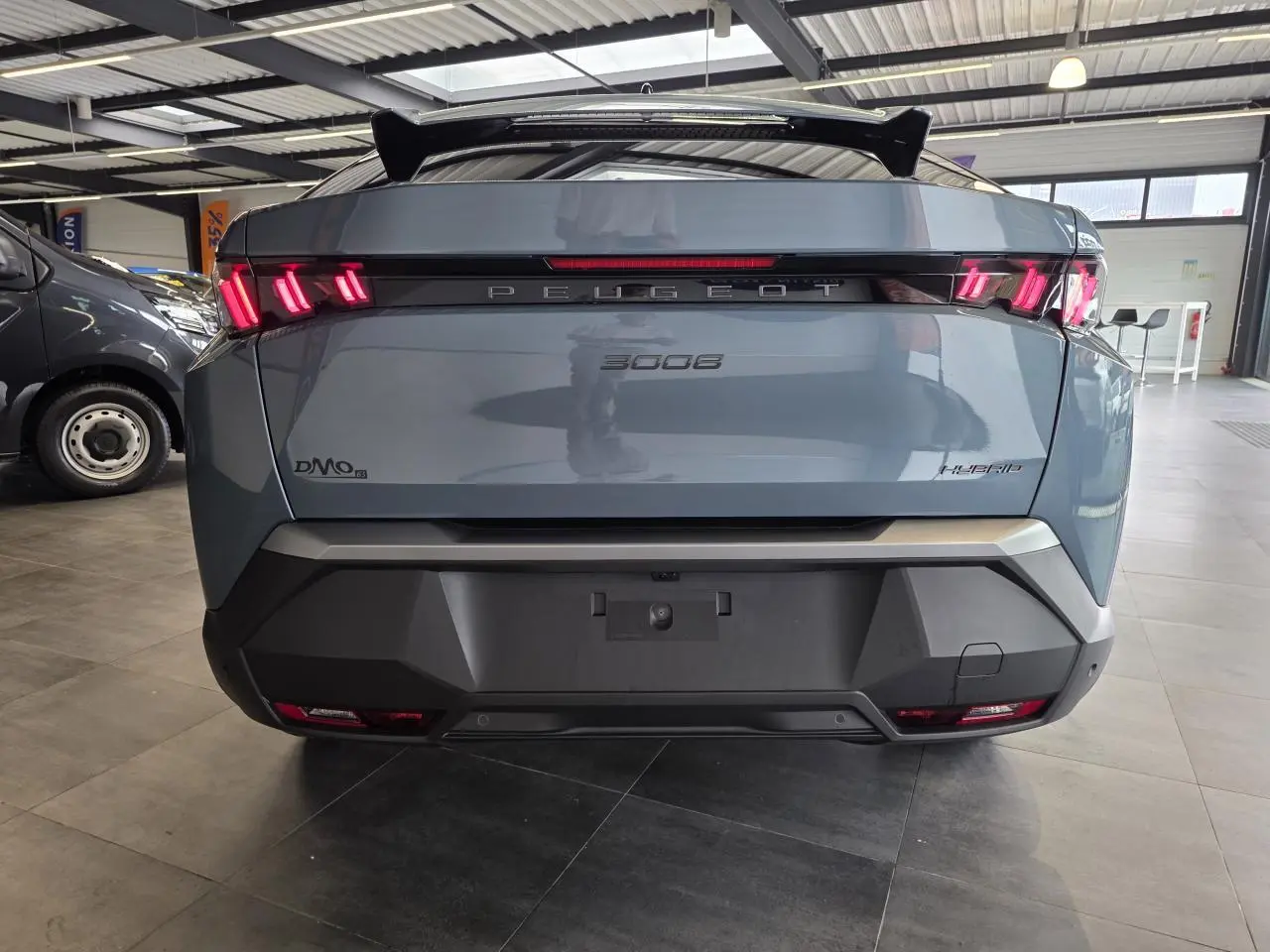 Vue arrière d'un Peugeot 3008 hybride bleu avec feux arrière LED à 3 griffes et bandeau noir laqué Peugeot.