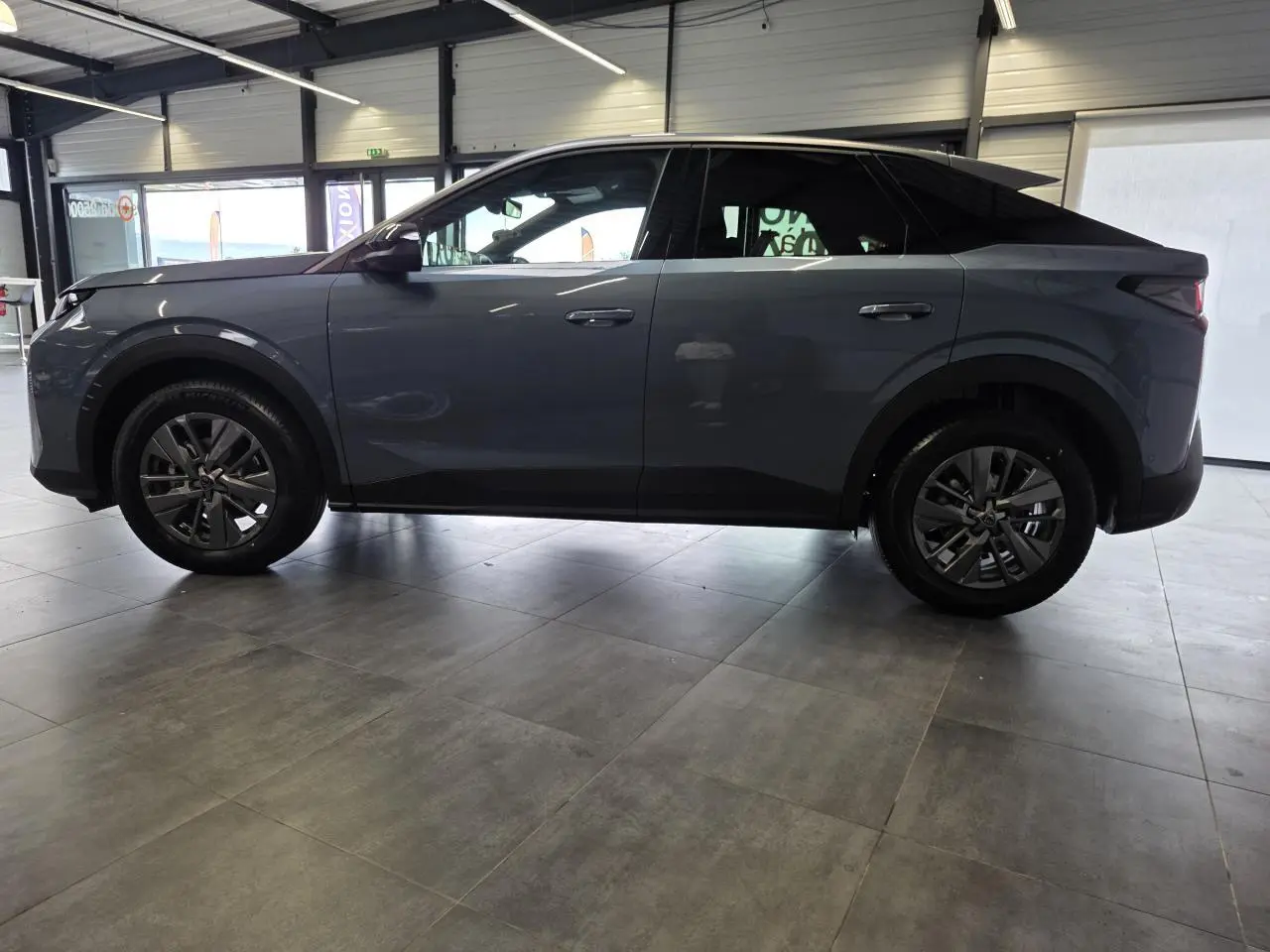 Vue latérale droite du Peugeot 3008 hybride bleu métallisé avec jantes alliage 18 pouces dans un showroom intérieur.