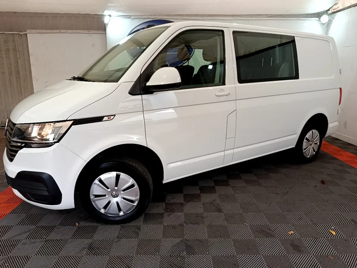 Vue de profil côté gauche d'un Volkswagen Transporter blanc 2.0 TDi 150 DSG7 Business avec vitres arrière teintées.