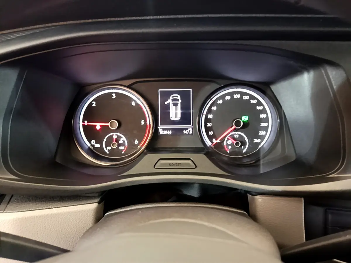 Tableau de bord du Volkswagen Transporter blanc 2021, affichage digital central et compteurs analogiques éclairés.