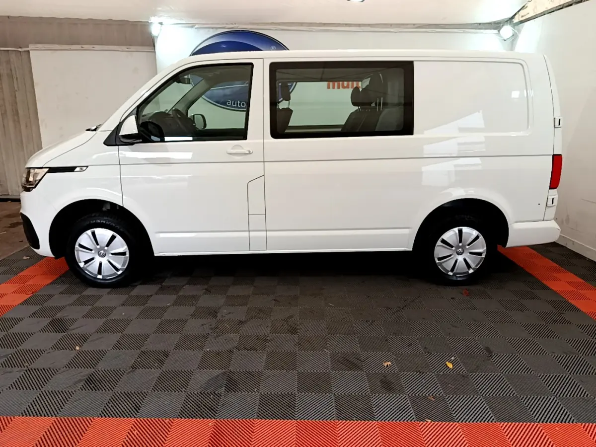 Profil côté gauche d'un Volkswagen Transporter blanc 2021, version 2.0 TDi 150 DSG7 Business en intérieur showroom.