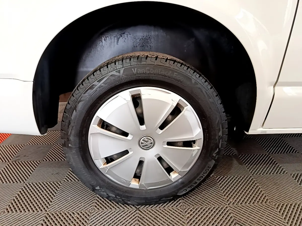 Gros plan sur la roue avant gauche blanche du Volkswagen Transporter 2.0 TDi 150 DSG7 Business avec enjoliveur d'origine.