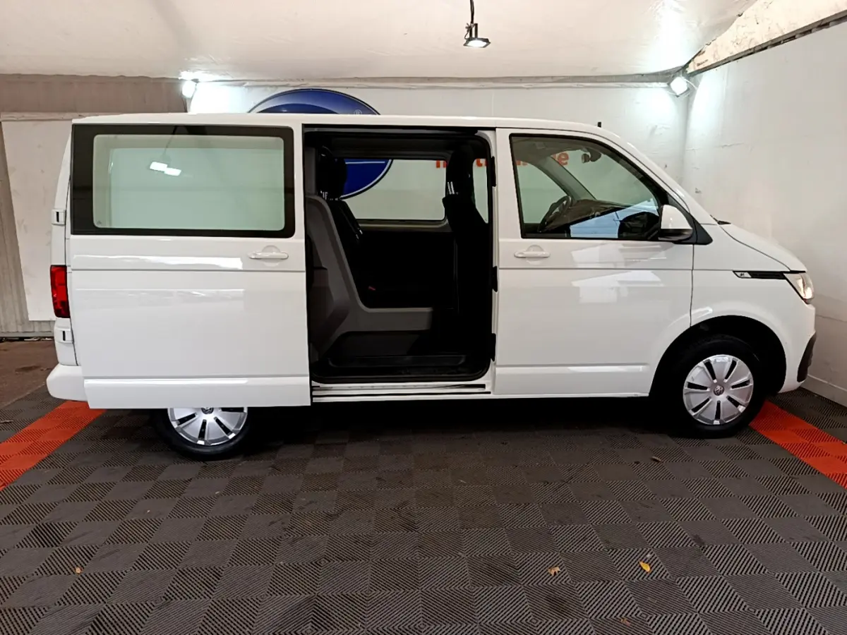 Profil droit du Volkswagen Transporter blanc 2021 avec porte coulissante ouverte dévoilant l'intérieur.