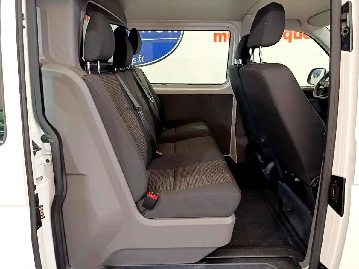 Vue intérieure côté droit du Volkswagen Transporter blanc 2021, banquette arrière trois places en tissu gris.