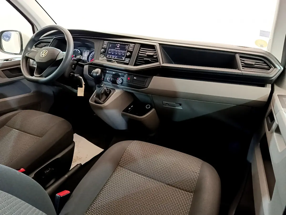 Intérieur du Volkswagen Transporter 2021, vue côté conducteur sur tableau de bord et sièges tissu gris foncé.