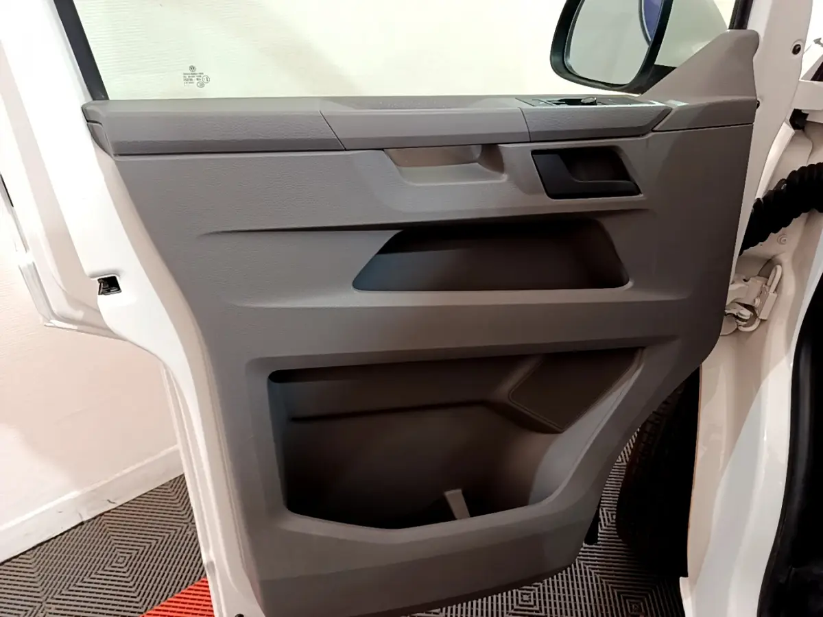 Vue rapprochée de la porte avant gauche blanche du Volkswagen Transporter 2.0 TDi 150 DSG7 Business avec rangement intégré.
