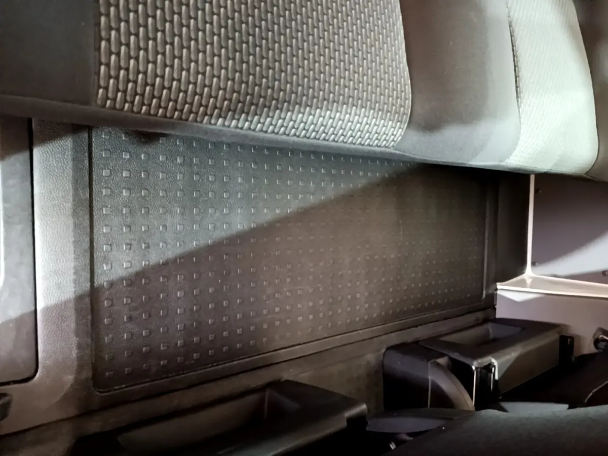 Vue intérieure du plancher arrière noir avec tapis caoutchouc et partie inférieure des sièges du Volkswagen Transporter blanc