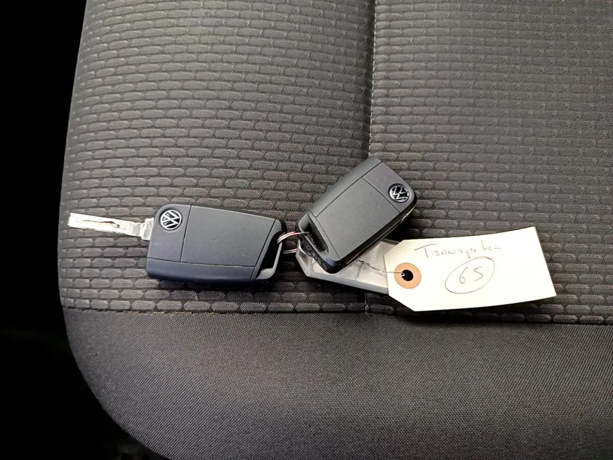 Clé Volkswagen posée sur un siège tissu gris foncé à motifs, intérieur du Transporter 2.0 TDi 150 DSG7 Business.