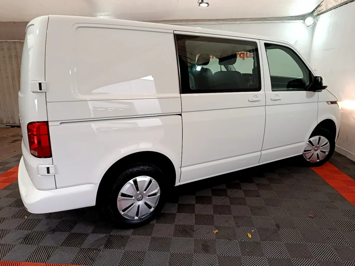 Vue 3/4 arrière droite d'un Volkswagen Transporter blanc avec vitres teintées et jantes acier en intérieur.
