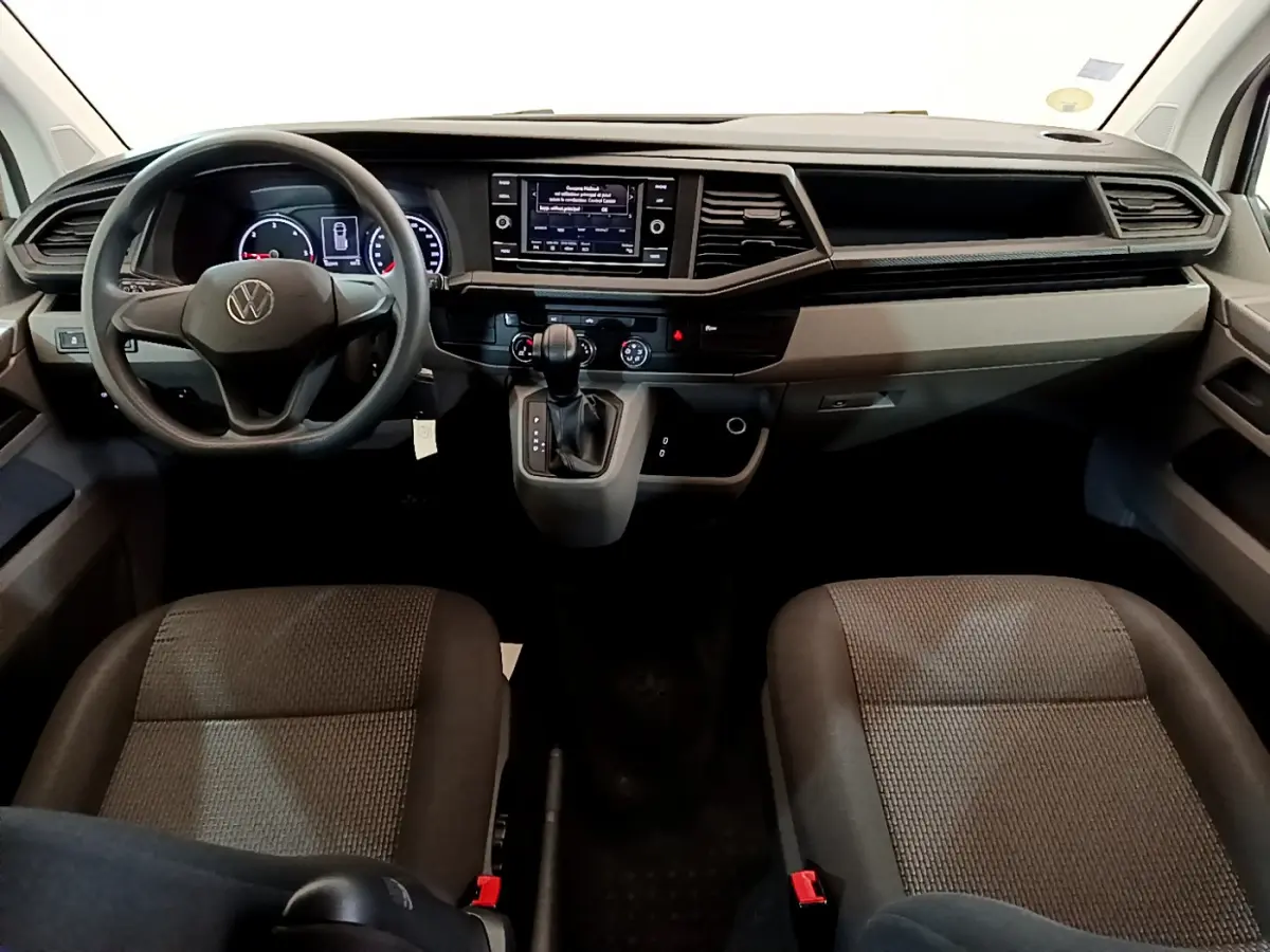 Intérieur avant du Volkswagen Transporter blanc 2021, tableau de bord moderne avec écran tactile et volant multifonction.