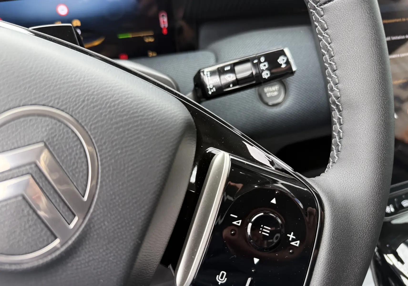 Gros plan sur le volant du Citroën C5 Aircross II Hybrid 2026 avec commandes intégrées et bouton start/stop visible en arrière-plan.