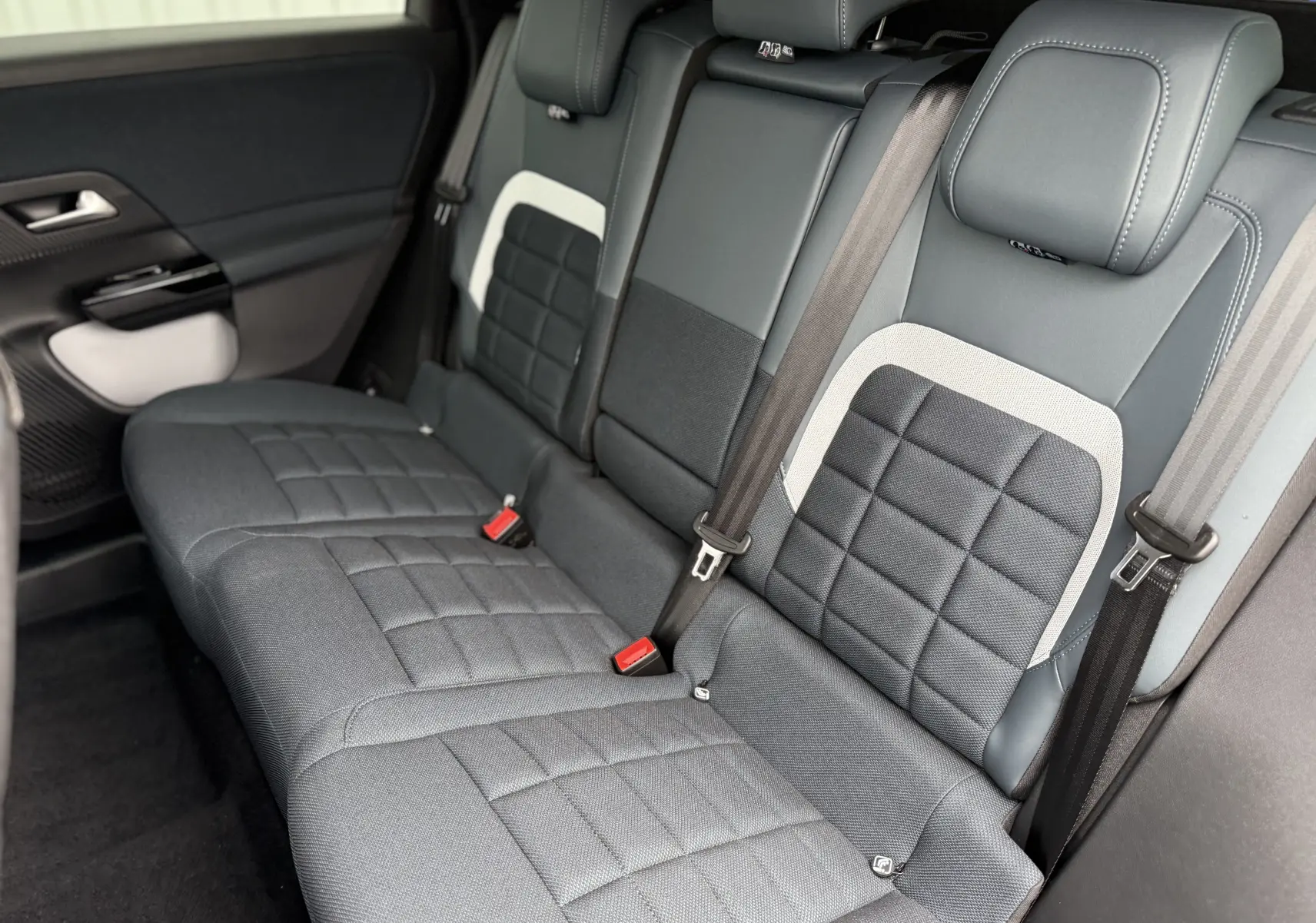 Vue intérieure en léger angle arrière droit des sièges arrière gris anthracite avec surpiqûres et ceintures de sécurité du Citroën C5 Aircross II Hybrid.