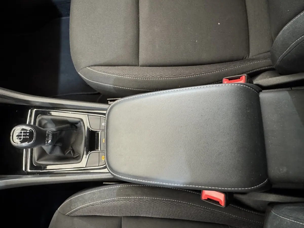 Vue rapprochée de l’accoudoir central noir et levier de vitesses manuel dans l’habitacle du Skoda Karoq blanc 2024.