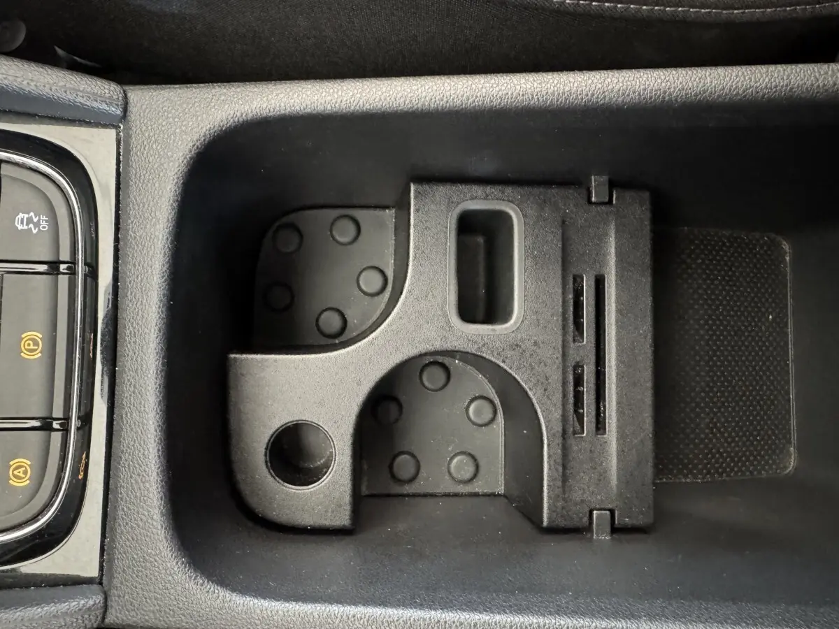 Gros plan sur le rangement central noir avec porte-cartes et commandes électroniques du Skoda Karoq blanc 2024.