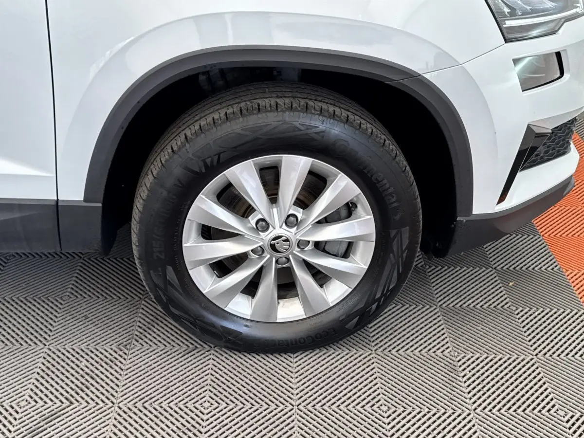 Gros plan sur la roue avant droite d’un SUV SKODA KAROQ blanc, avec jante alliage et pneu Continental.