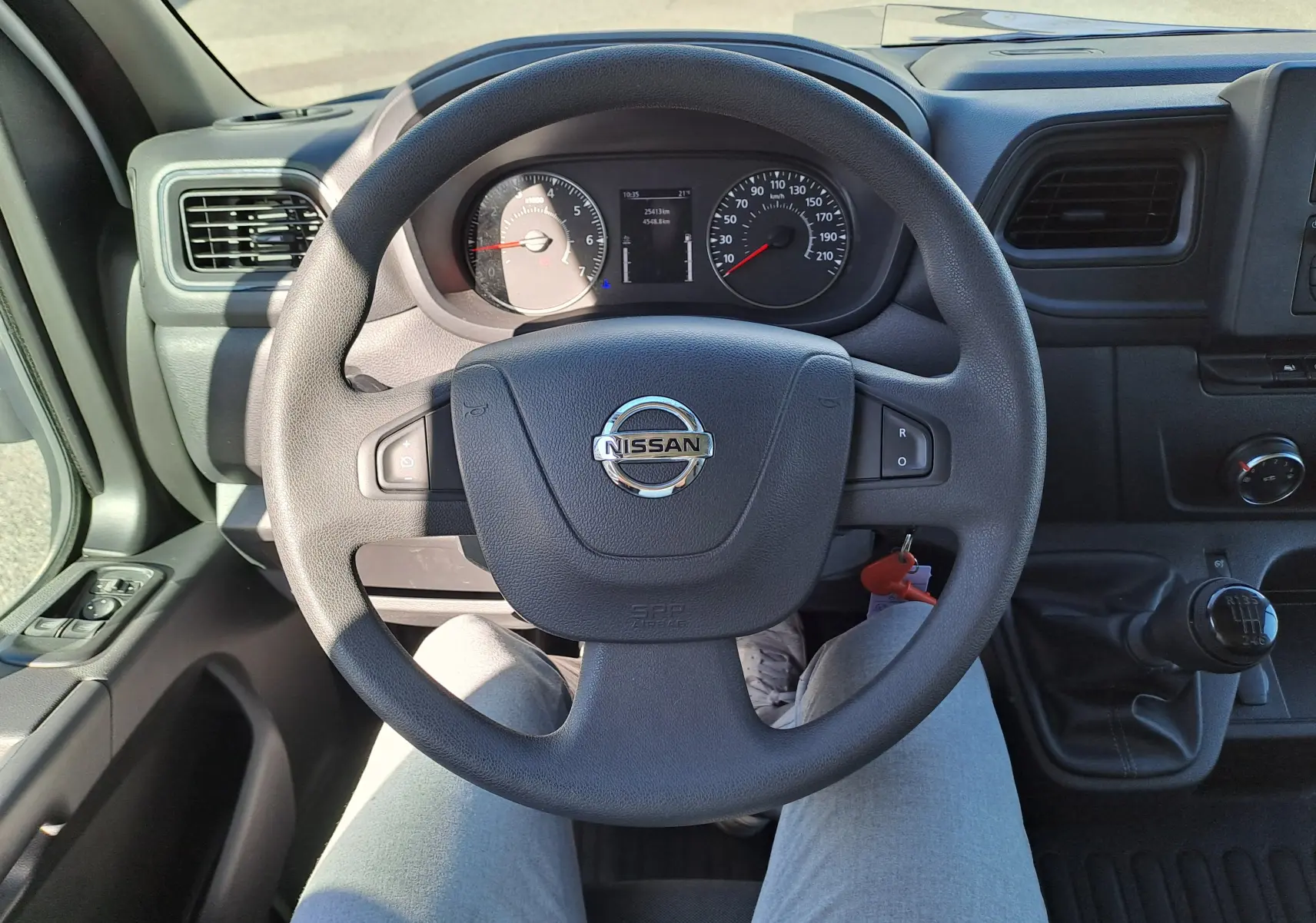 Vue intérieure centrée sur le volant Nissan d'un Interstar Chassis Cabine blanc 2024 avec boîte manuelle et tableau de bord visible.