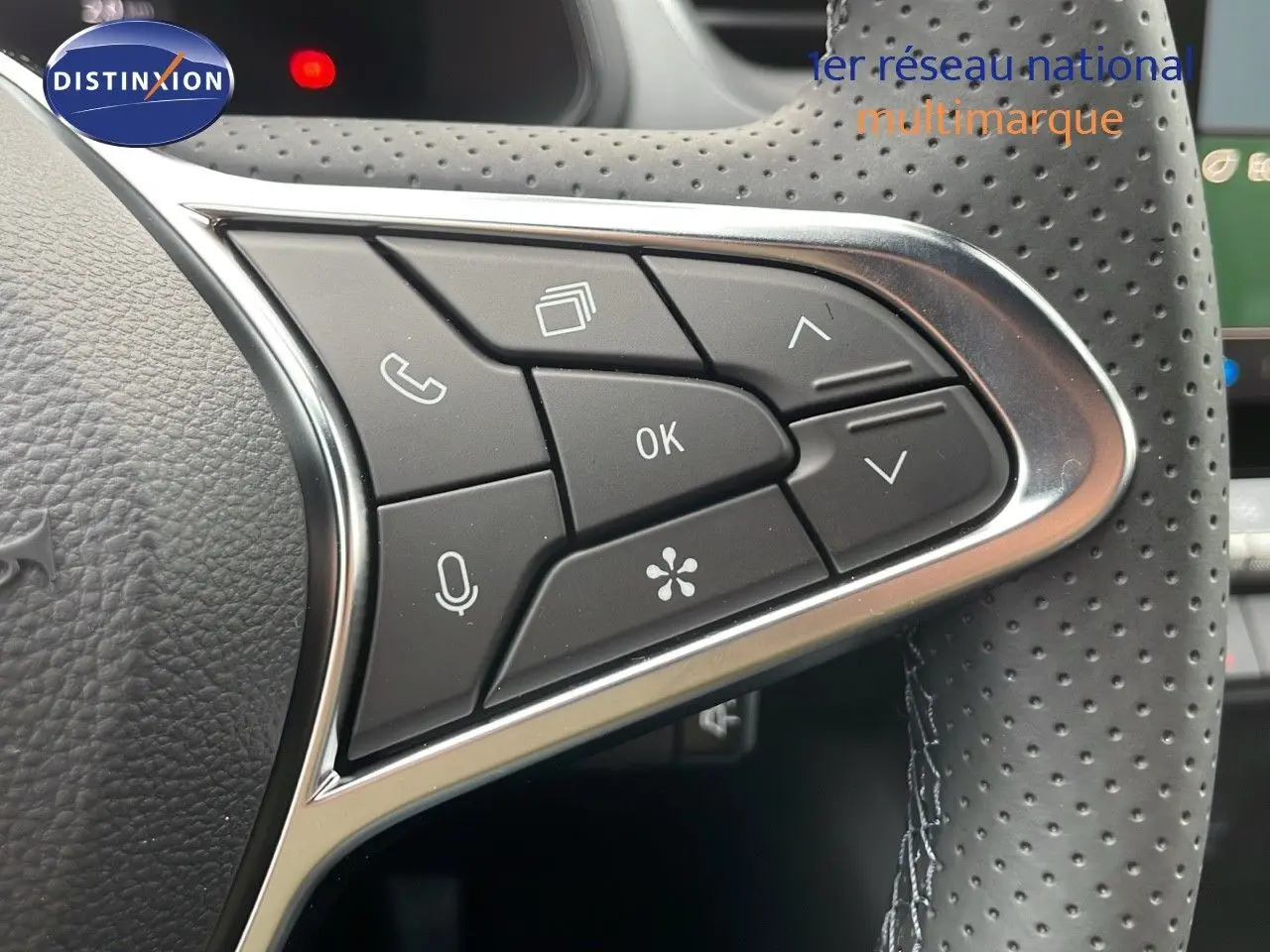 Gros plan sur les commandes multifonctions à droite du volant perforé du Renault Captur E-Tech blanc nacré 2025.