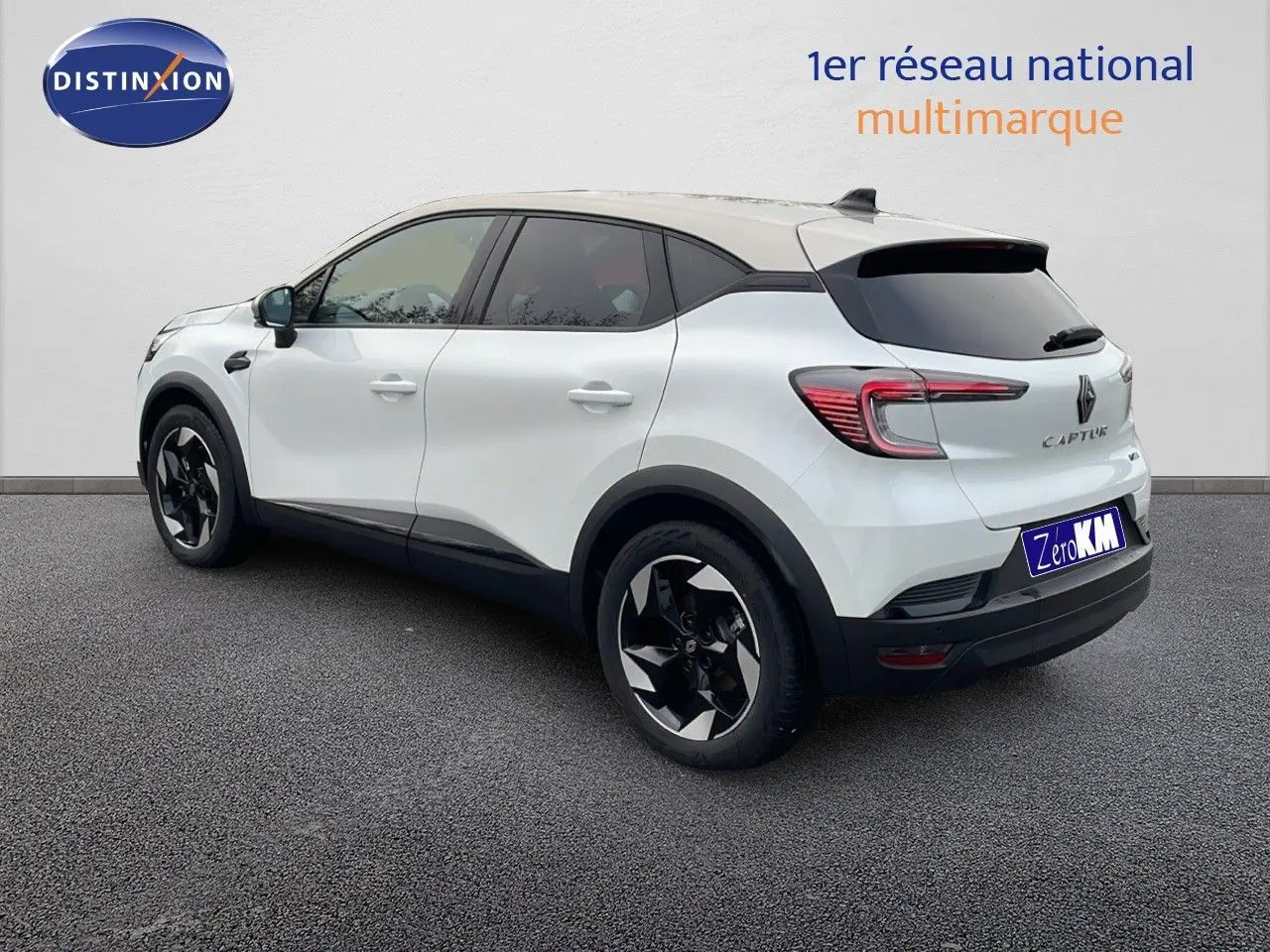 Vue 3/4 arrière droite du Renault Captur blanc nacré avec toit beige et jantes noires au design moderne.