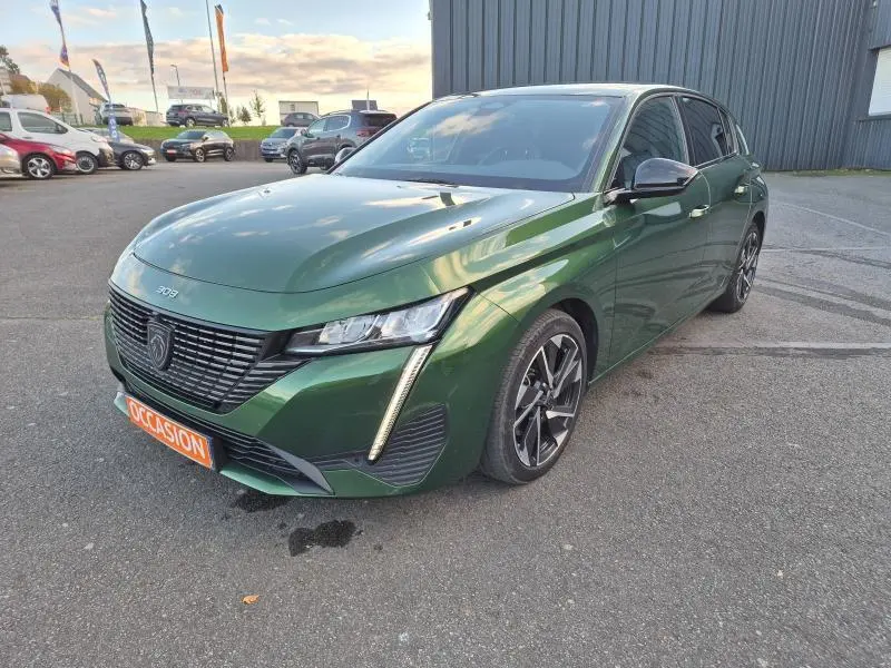 Peugeot 308 vert olivine vue 3/4 avant droit, avec calandre noire et feux LED verticaux distinctifs.
