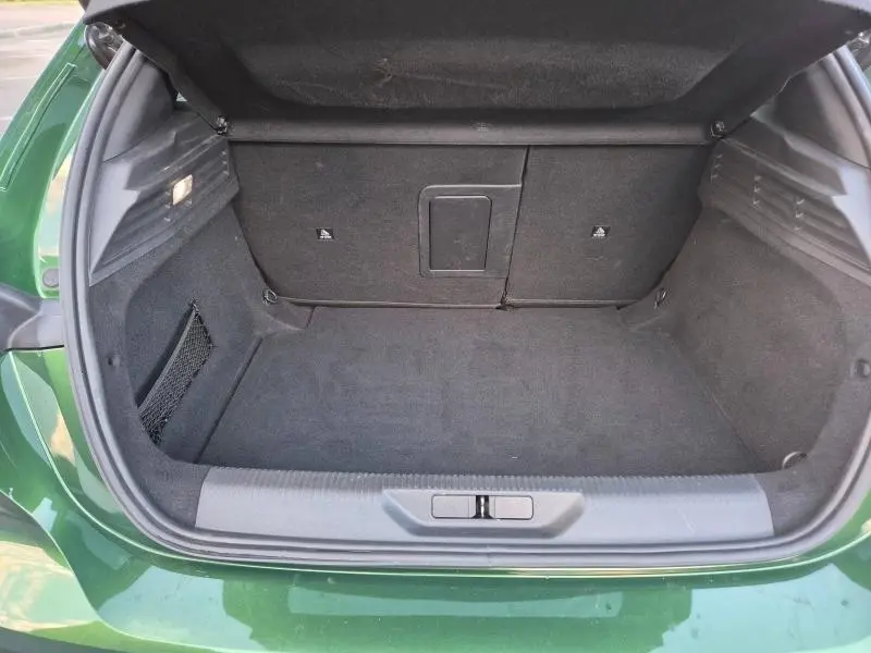 Coffre ouvert vu de l'arrière d'une Peugeot 308 1.5 BlueHDi vert olivine avec intérieur noir et filet latéral.