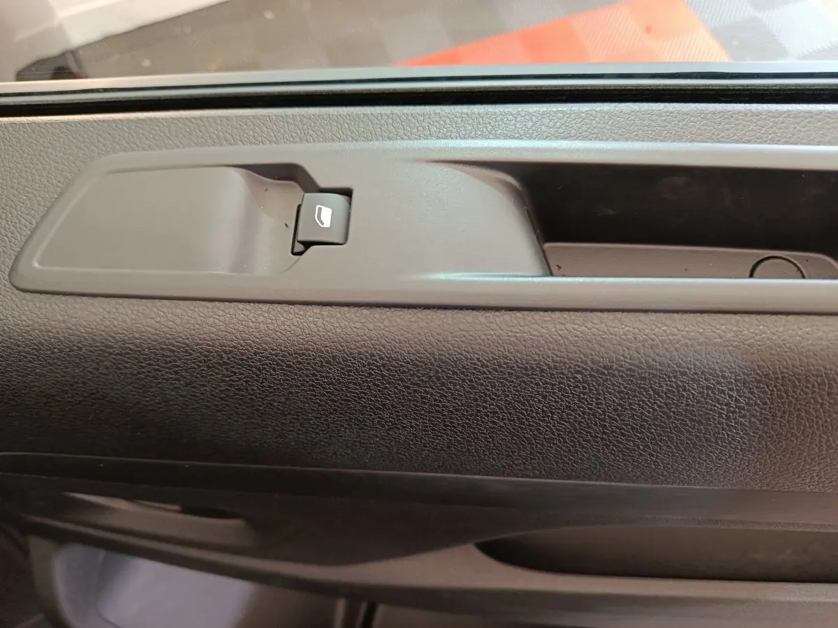 Gros plan sur la commande de lève-vitre intégrée à la porte intérieure noire du Citroën Jumpy XL 2025.