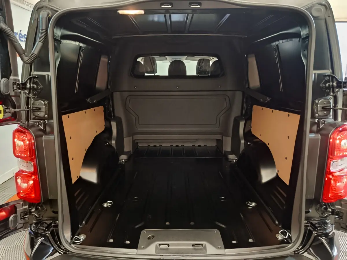 Vue arrière du coffre noir du Citroën Jumpy XL 2025, montrant l'espace de chargement avec cloisons latérales en bois.