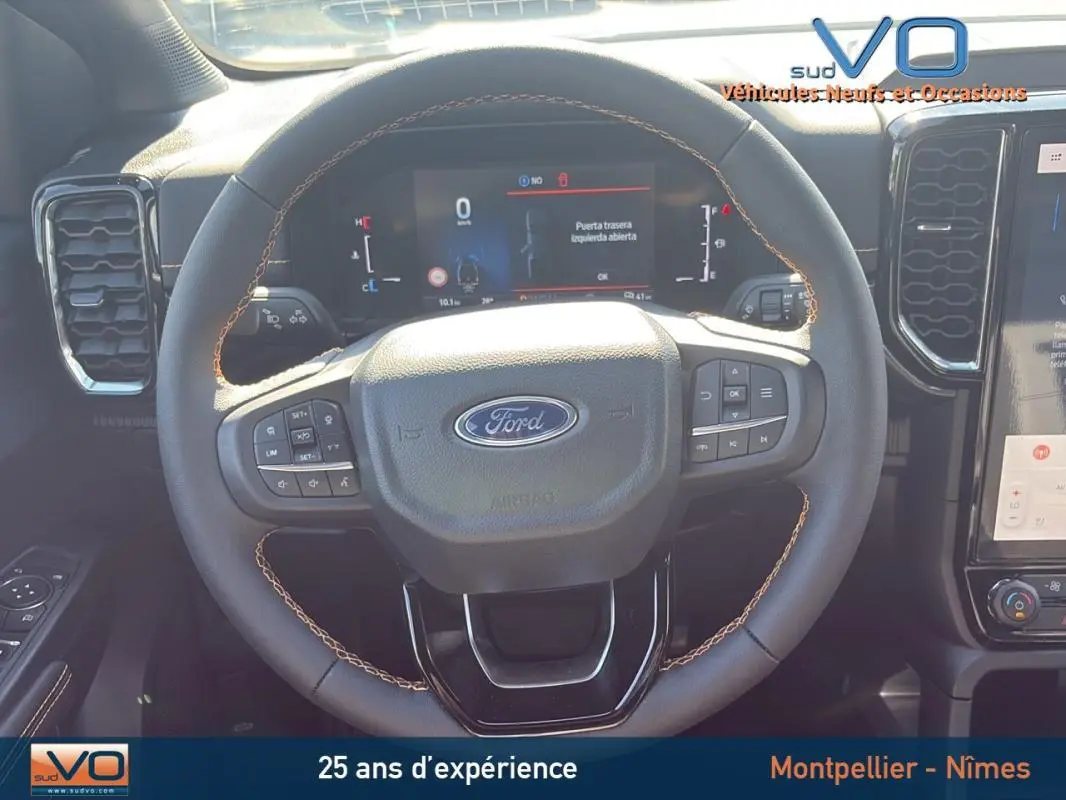 Vue rapprochée du volant multifonctions noir du Ford Ranger 2025, avec tableau de bord numérique et commandes intégrées.