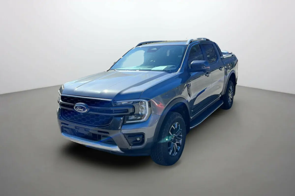 Ford Ranger 2.0 205 Wildtrak Plus gris carbone en 3/4 avant droit avec barres de toit et jantes alu 18 pouces.