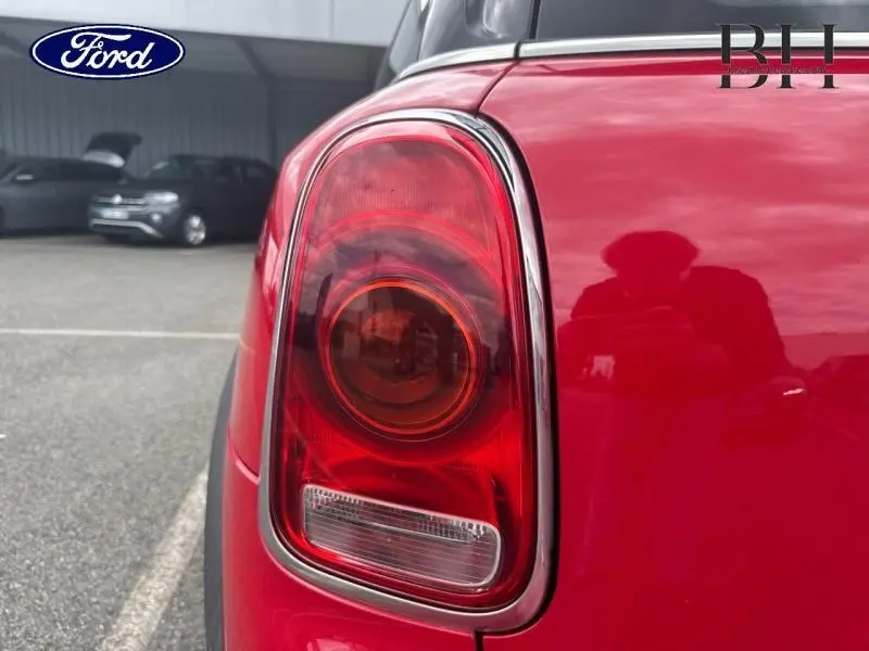 Gros plan sur le feu arrière droit chromé d'une MINI Countryman Chili Red, avec reflet du photographe sur la carrosserie.