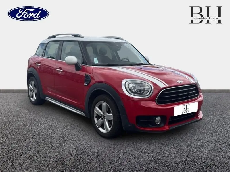 Vue 3/4 avant droite d'une MINI Countryman Cooper D 2018 chili red avec bandes blanches sur le capot et jantes alu.