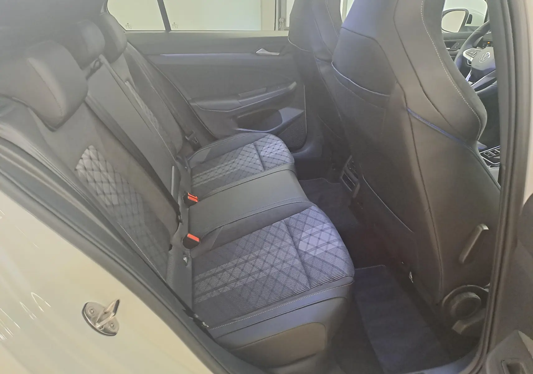 Vue intérieure arrière droite de la Volkswagen Golf 2.0 TDI blanche, montrant les sièges arrière en tissu et cuir noir avec motifs géométriques.