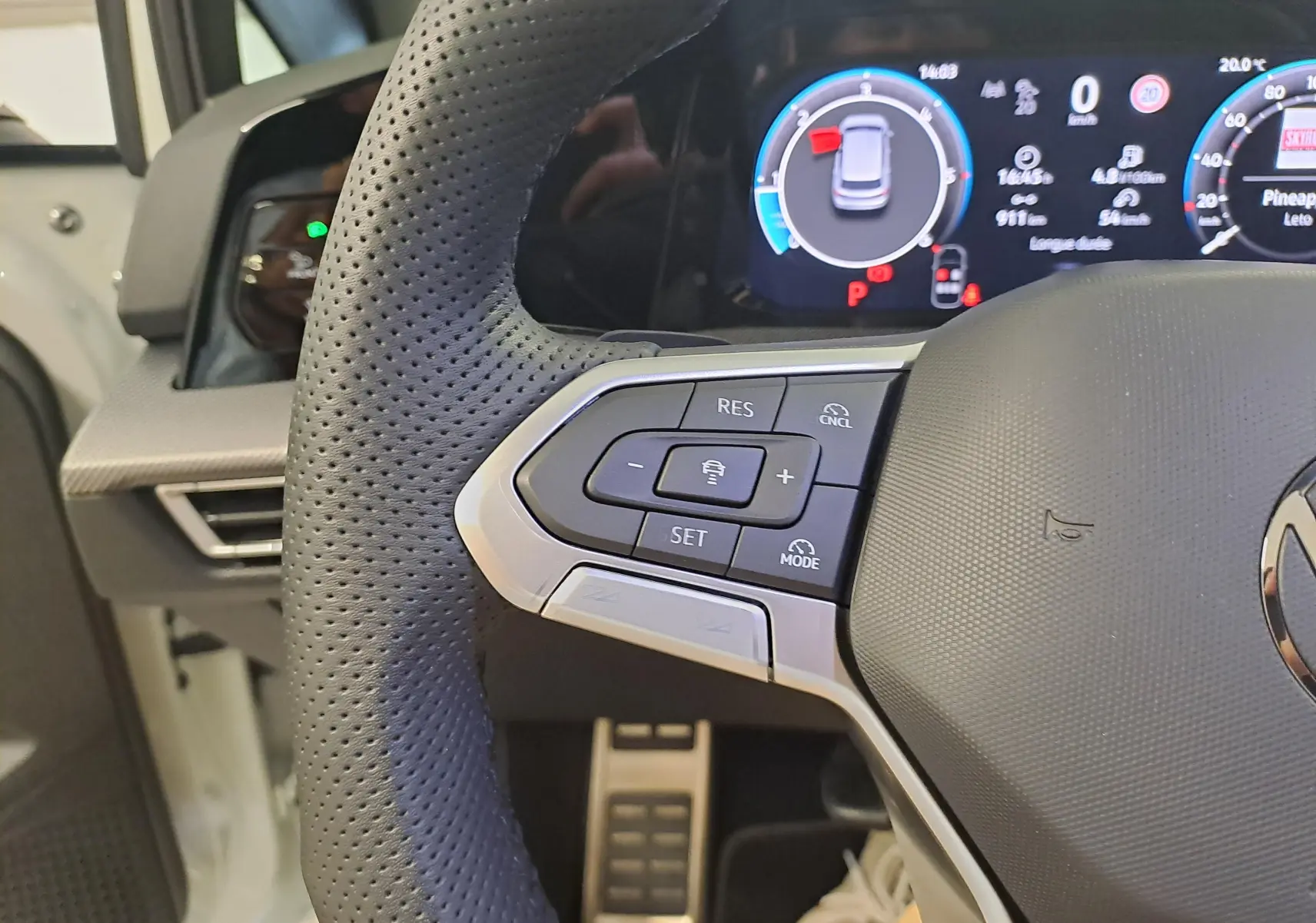 Gros plan sur le volant cuir perforé et les commandes multifonctions de la Volkswagen Golf 2.0 TDI blanc Oryx nacré.