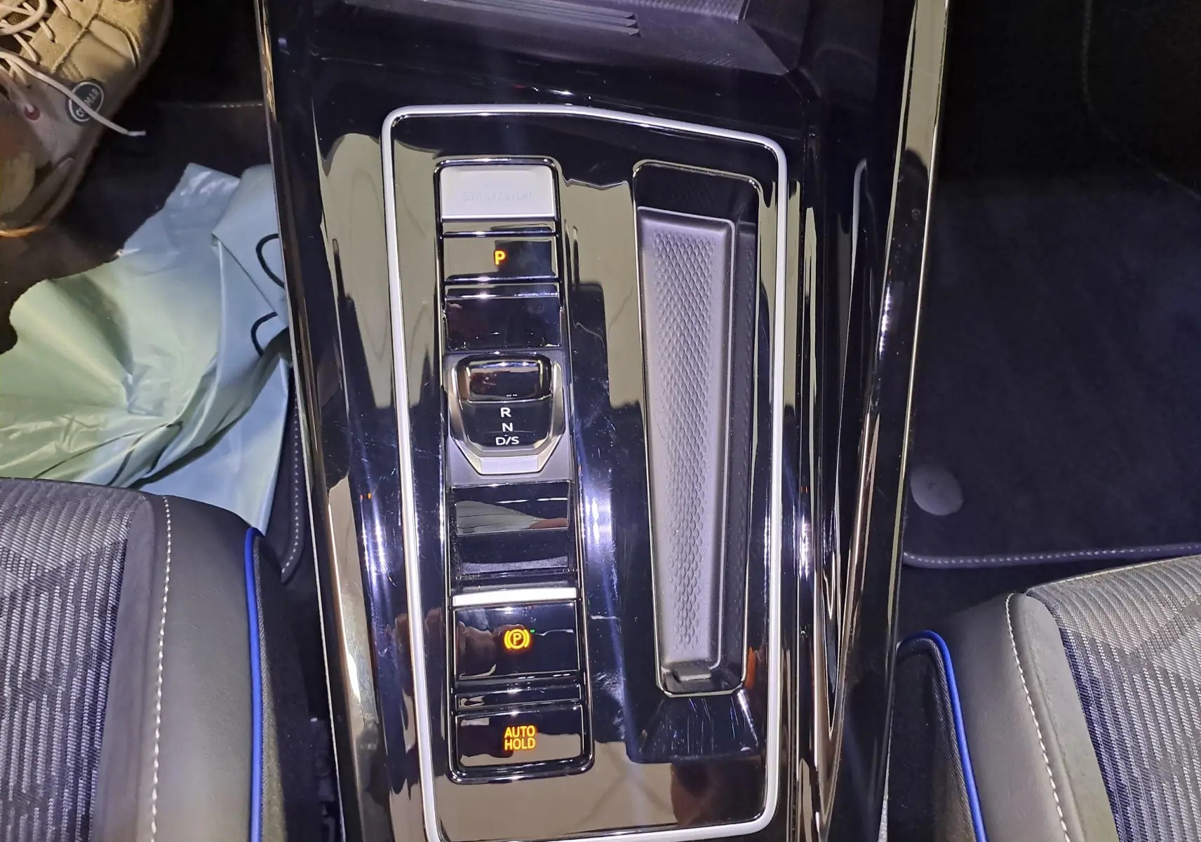 Vue plongeante sur la console centrale noire brillante de la Volkswagen Golf 2025 avec sélecteur de vitesse électronique.