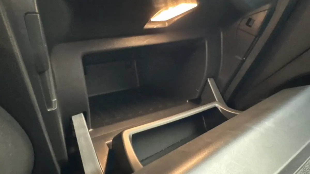 Gros plan sur la boîte à gants ouverte de la Renault Captur 2024, intérieur noir avec éclairage intérieur.